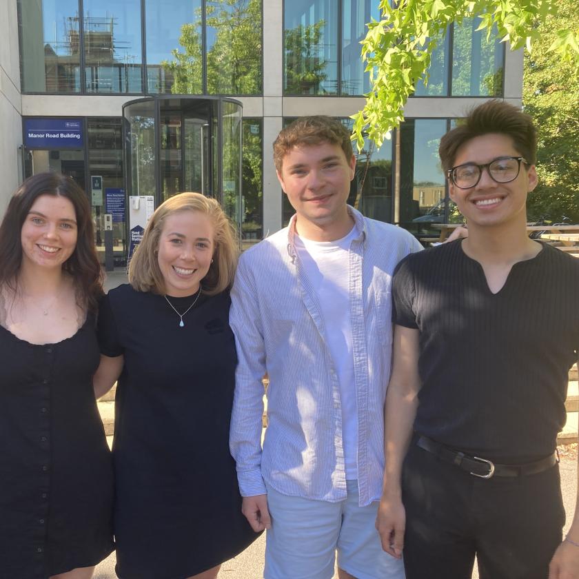 five people stand smiling in front of the Department buidling