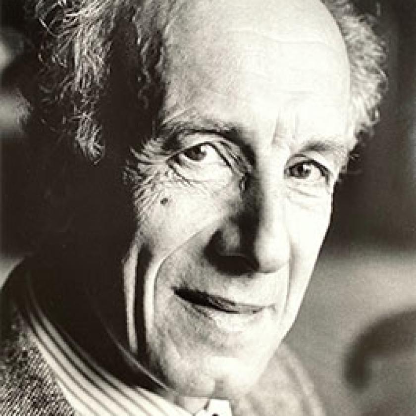 Side profile of a man wearing a suit and tie, smiling at the camera