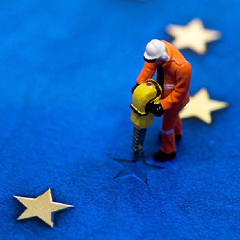 Graphic of a man in orange overalls and hardhat working a road drill on a star in the EU flag which is missing