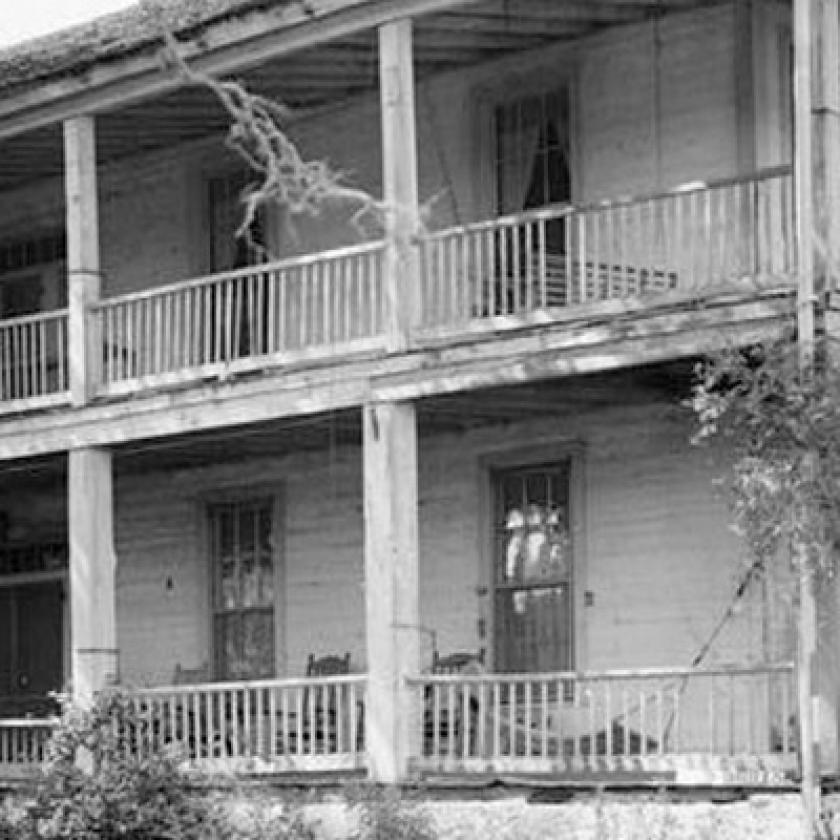 Black an white image of the front of a plantation house in Washington County, Texas, with a tree and grass in front of it