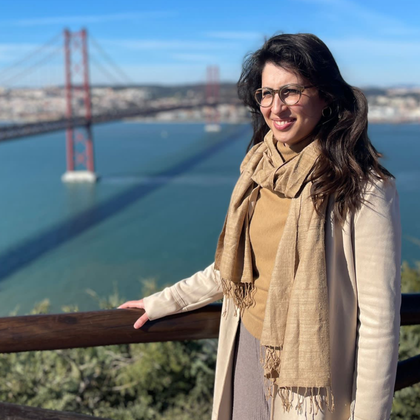 a woman smiling and looking past the camera, with San Francisco's Golden Gate Bridge in the background