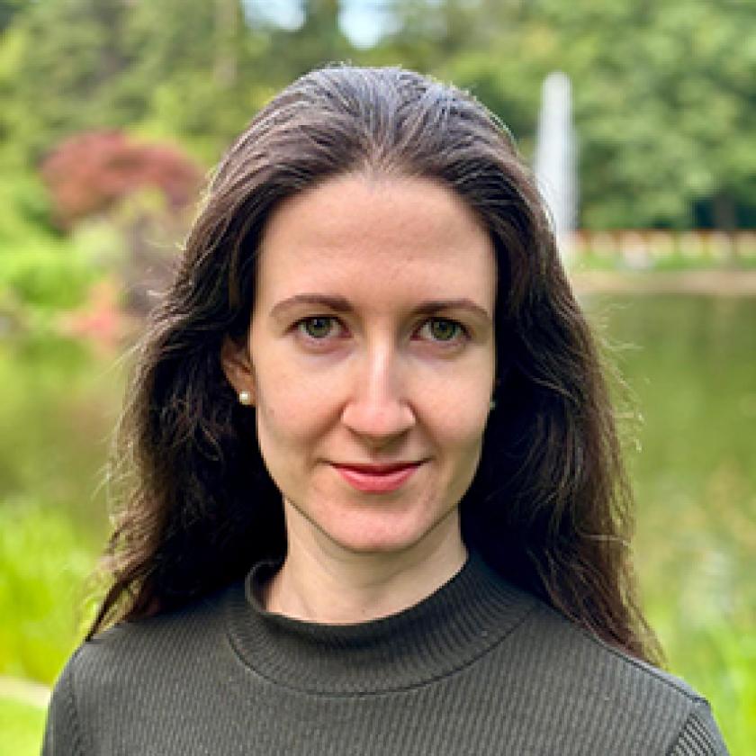 A person with long hair in front of a pond.