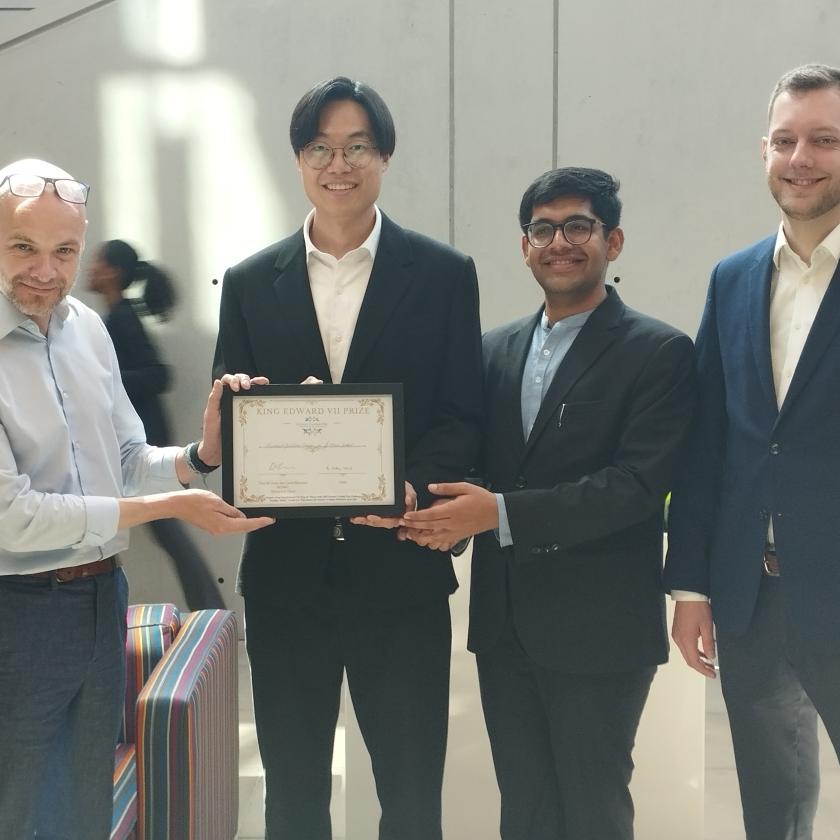 image of four men looking at the camera holding a prize certificate