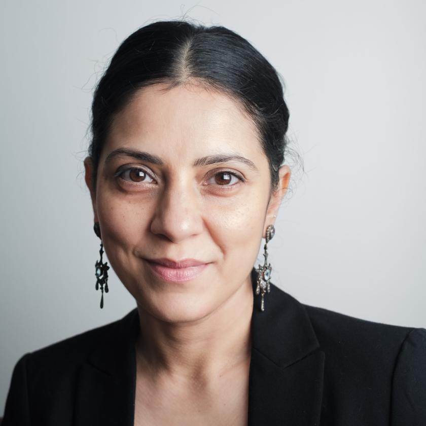 Image of a woman in a black suit smiling at the camera