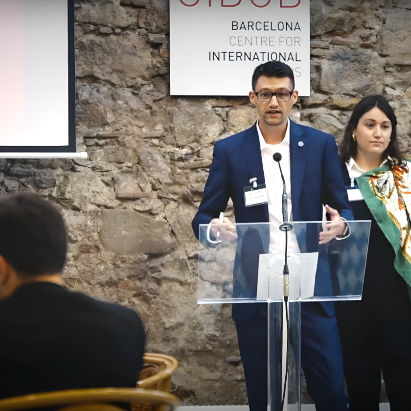 A person standing at a podium with a person standing behind him