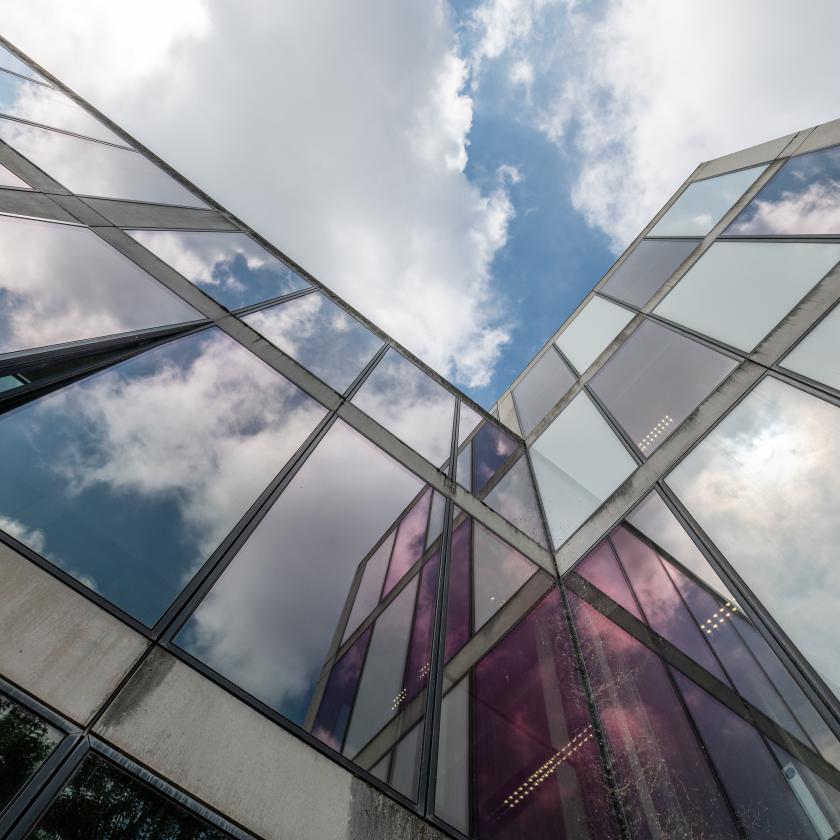 photo shot upwards of the glass sides of a building with a cloudy sky visible