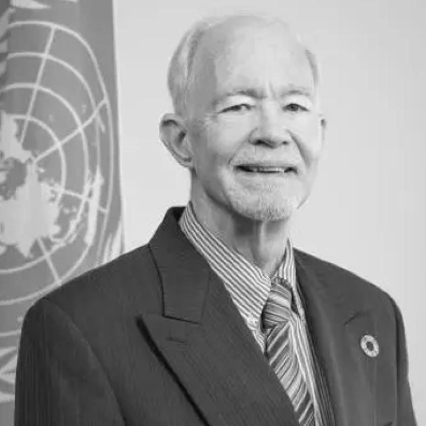 black and white image of a man wearing a suit and tie smiling at the camera