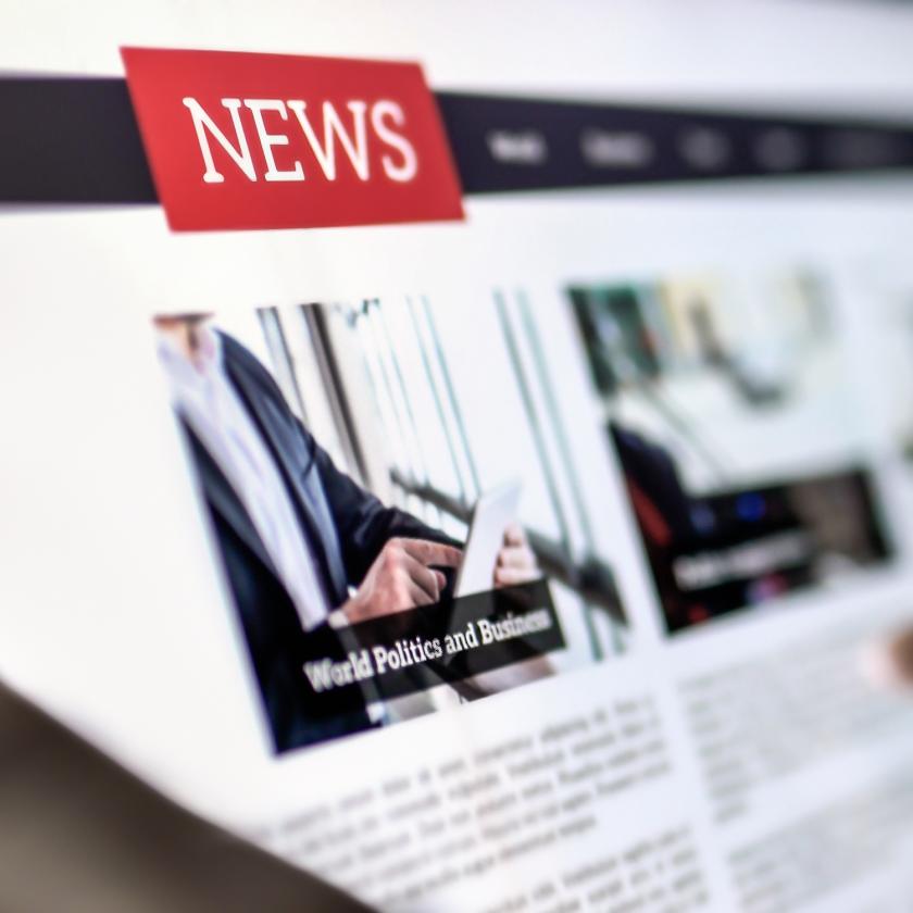 Image of hands holding a tablet screen with writing on including the word ‘NEWS’