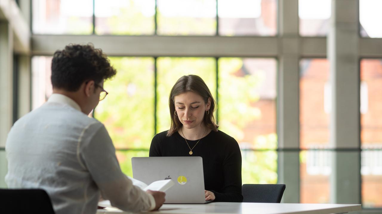 Woman on laptop, man reading book