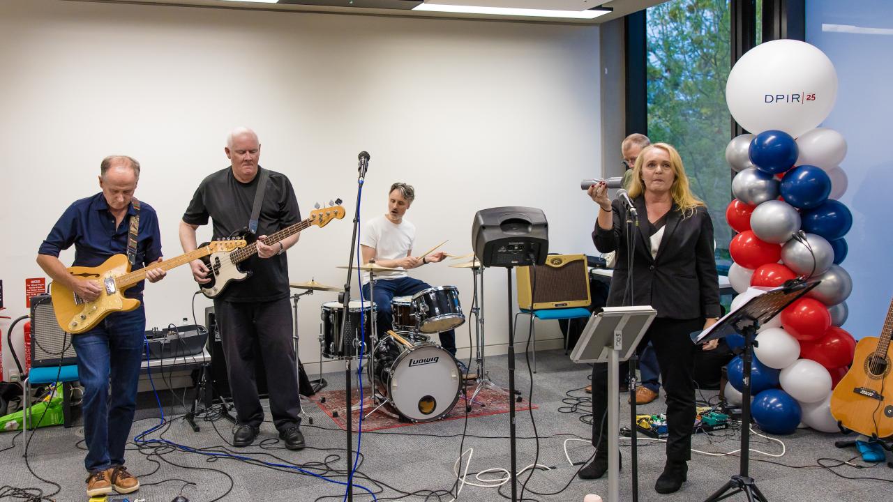 image of a band playing with balloons to the right of them