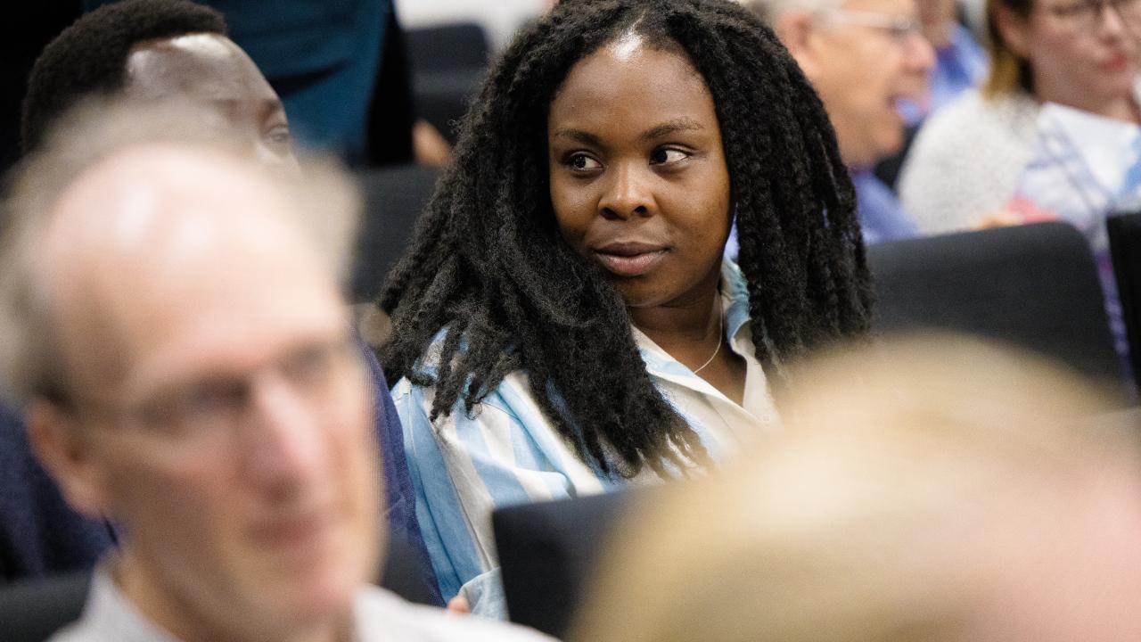 Image of a woman looking to the side amid a seated audience