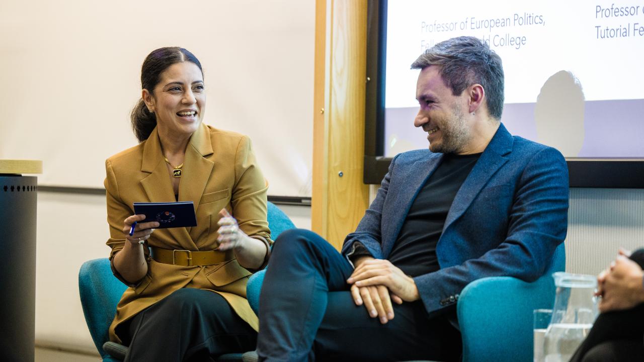 image of a man and a woman seated in front of a projector screen