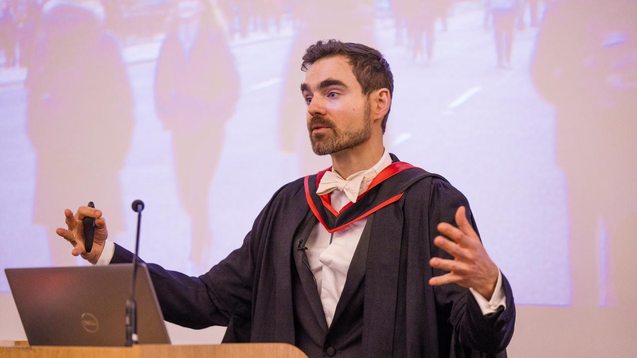 image of a man gesticulating in front of a lectern