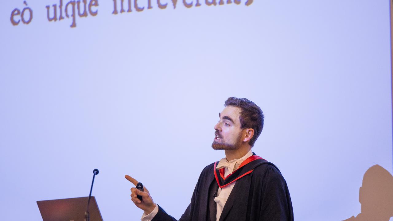 image of a man in front of a lectern in front of a projector screen