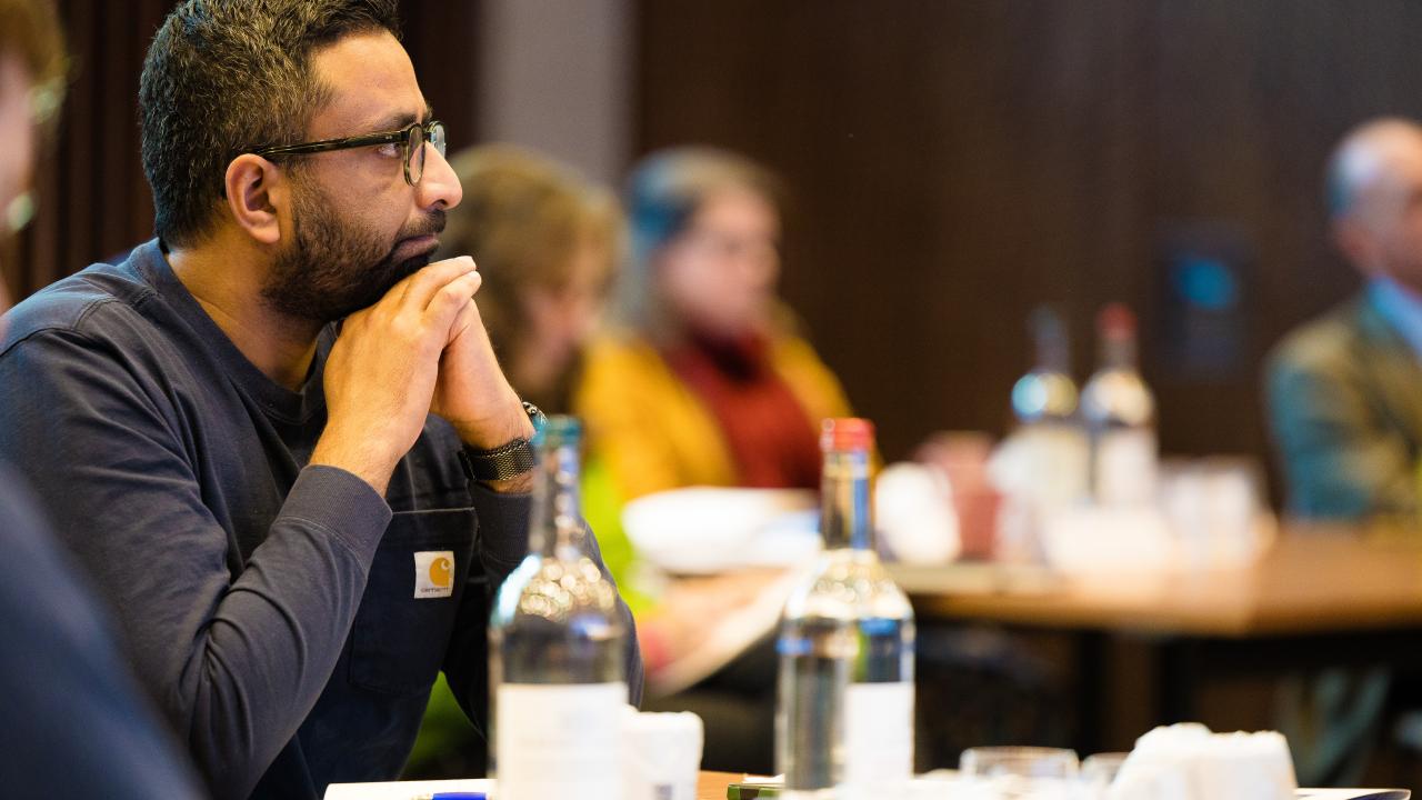 close up side image of a man seated at a table with people beside him