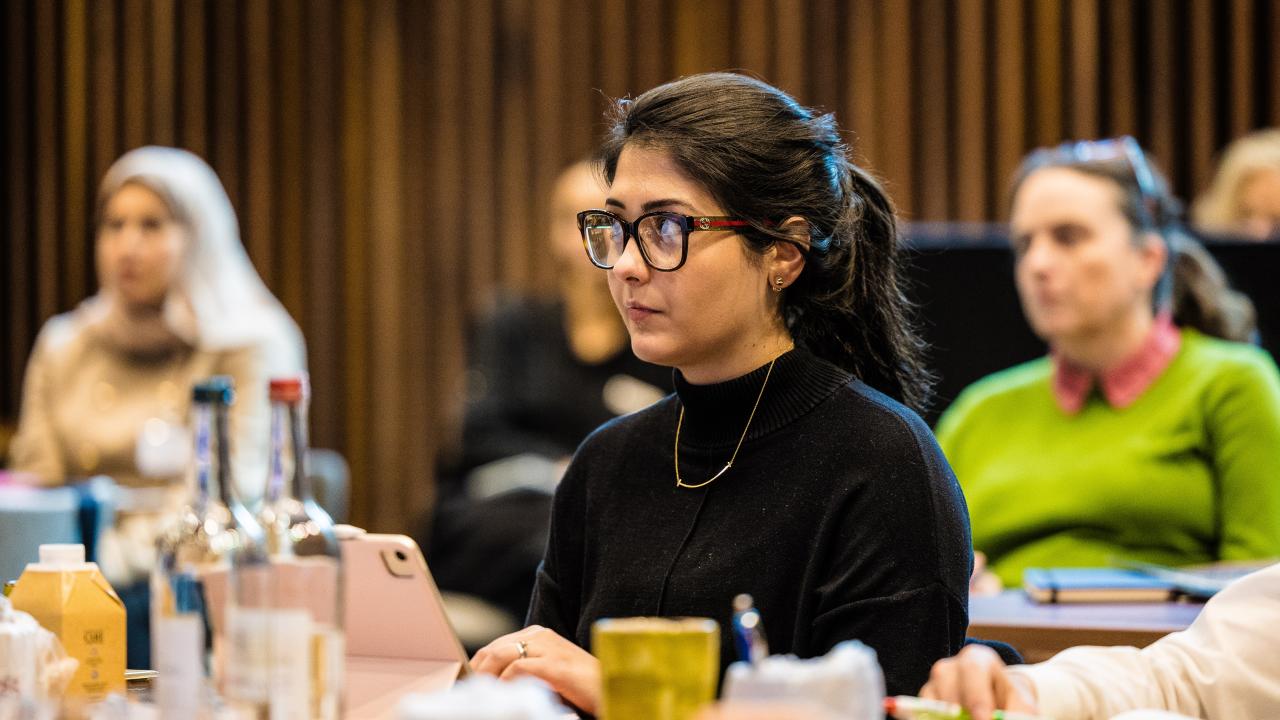 side image of a number of people sat listening to a lecture