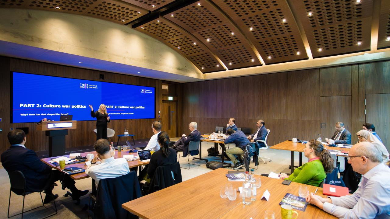 image of a large room with a projector screen at the front and a lecture taking place