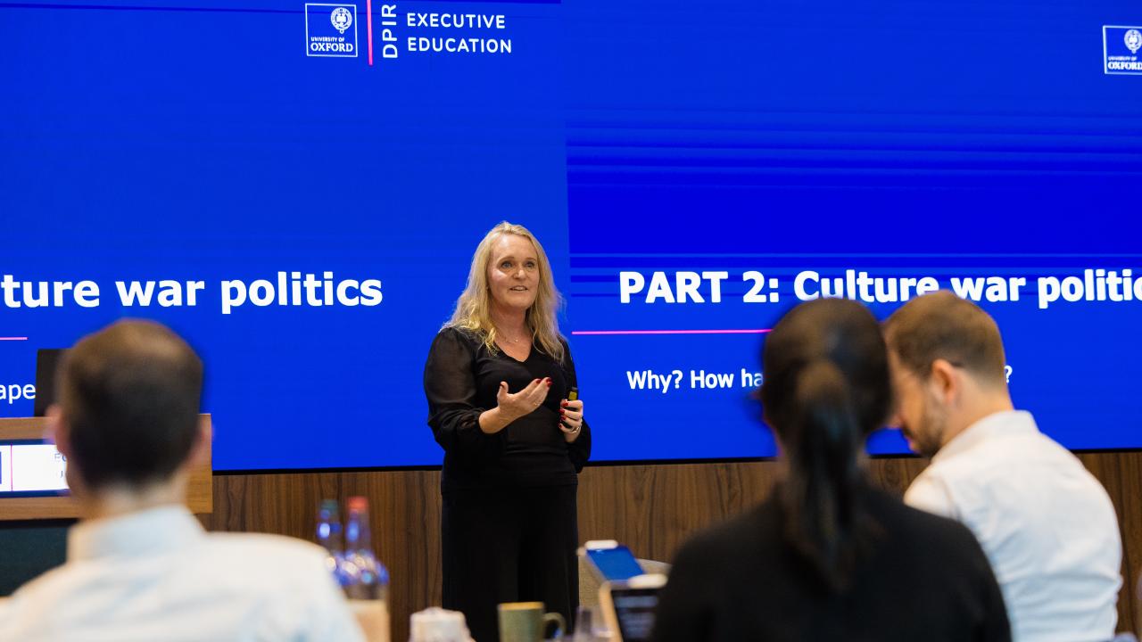 image of a woman in front of a projector screen giving a lecture