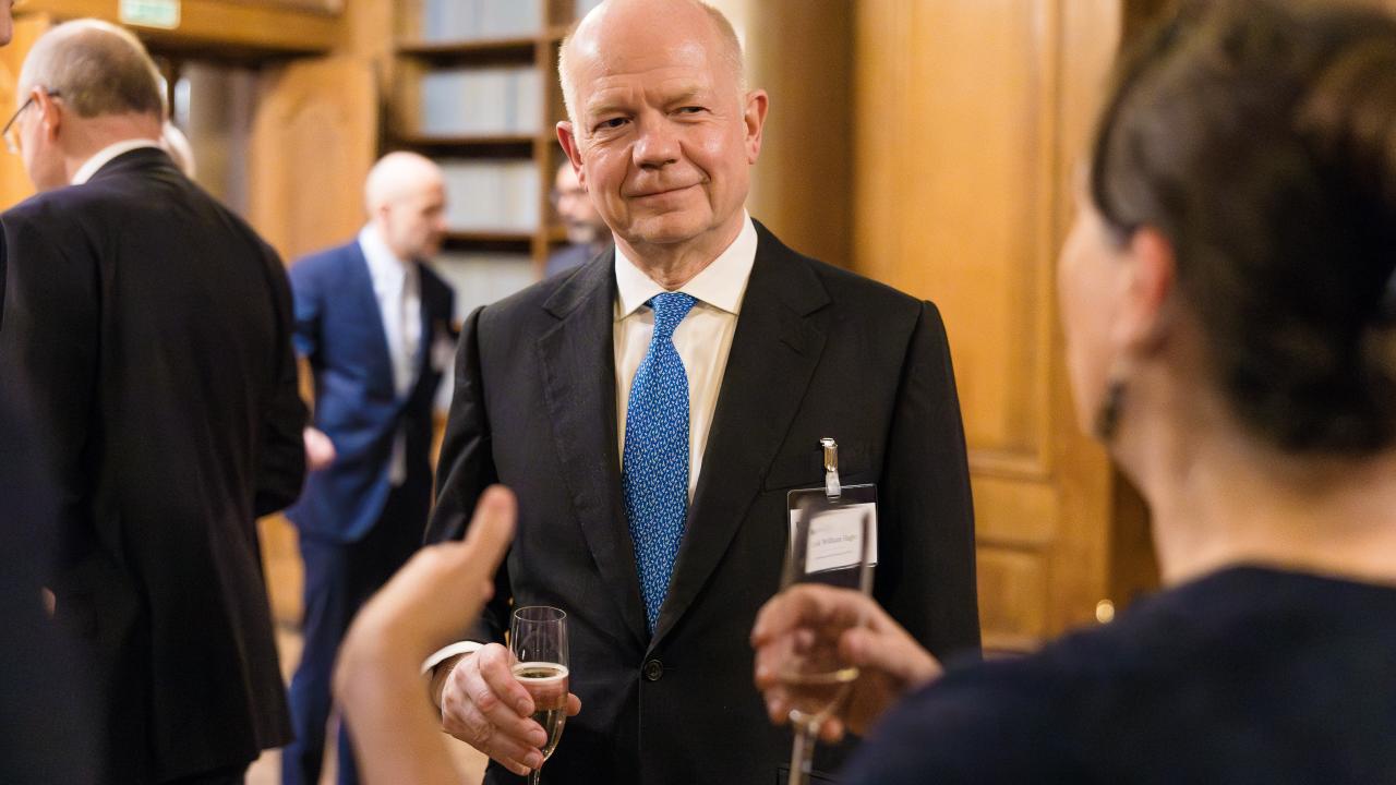 image of a woman with her back to the camera stood talking to a man