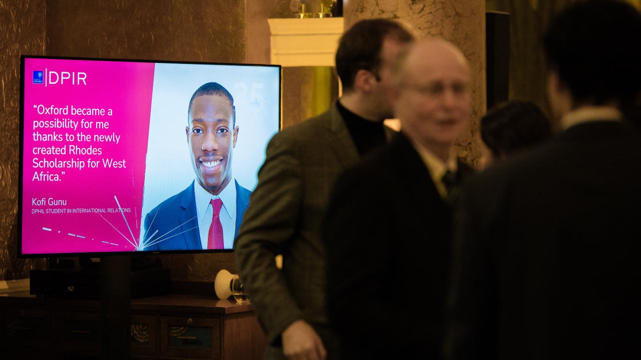 image of three people talking with a projector screen in the background