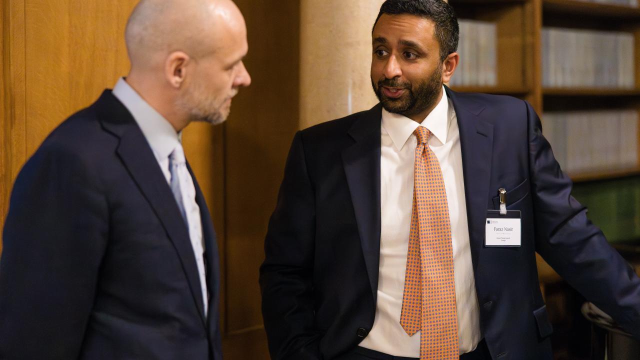 side image of a man stood talking to another man