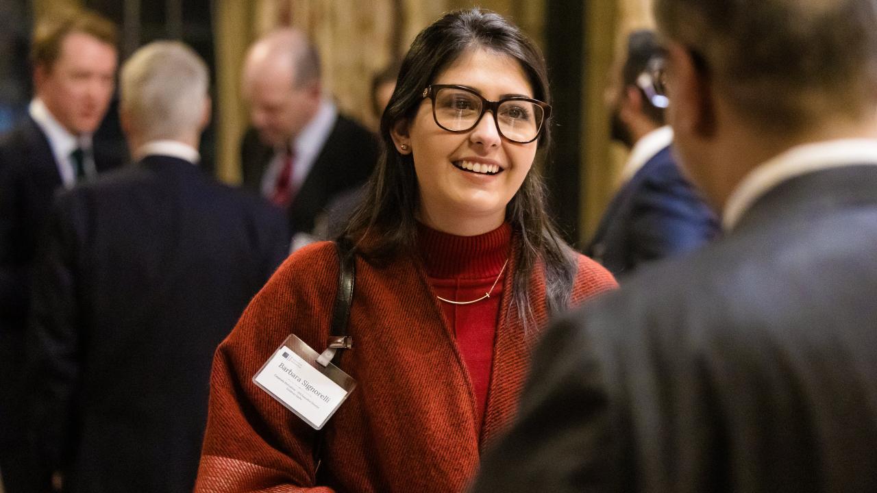 image of a man with his back to the camera stood talking to a woman