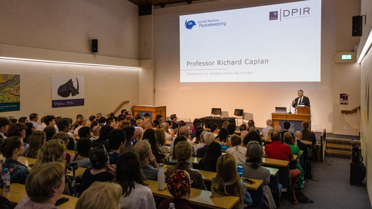 image taken from the back of a room where a lecture is taking place