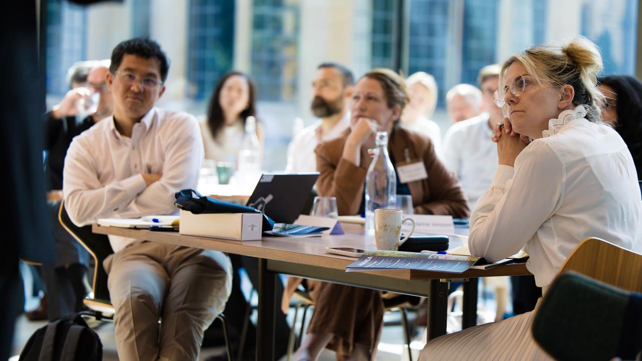 image of a group of people sat at tables listening to a lecture