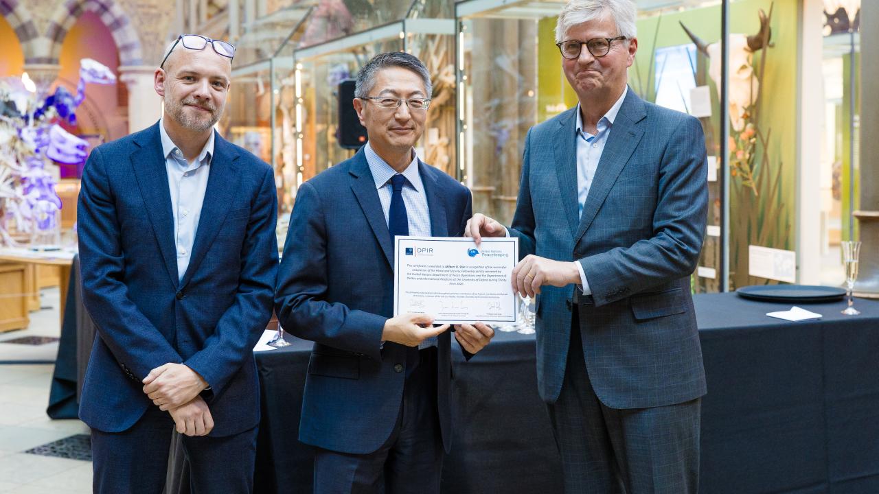 image of two men presenting a certificate to another man