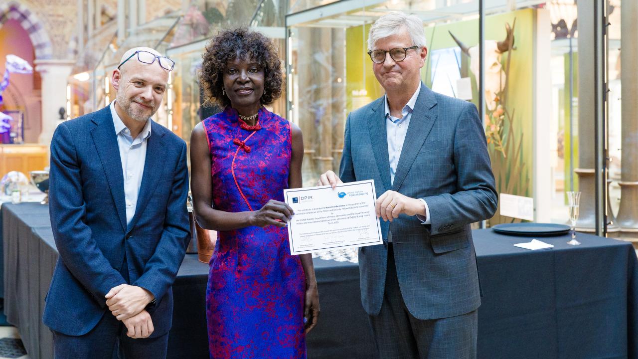 image of two men presenting a certificate to a woman