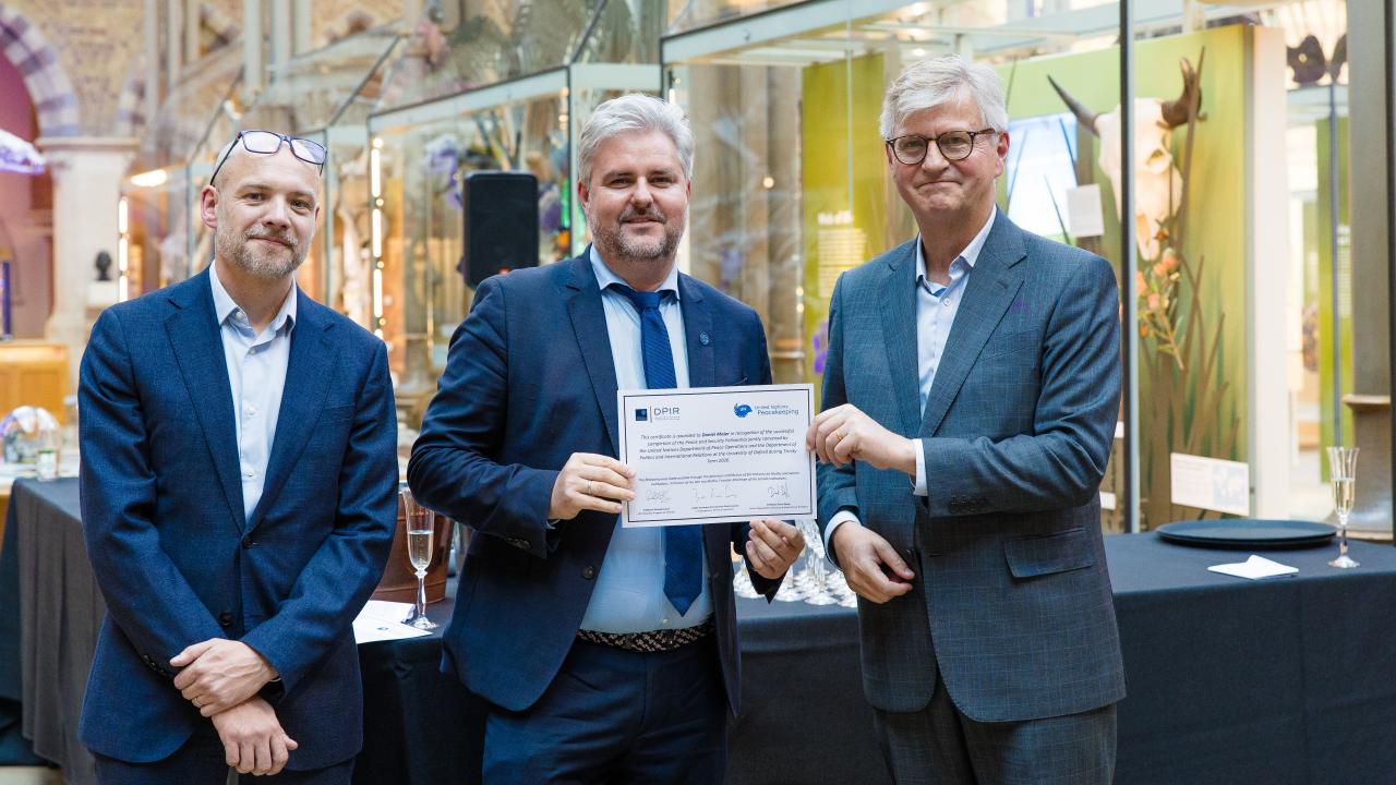 image of two men presenting a certificate to another man