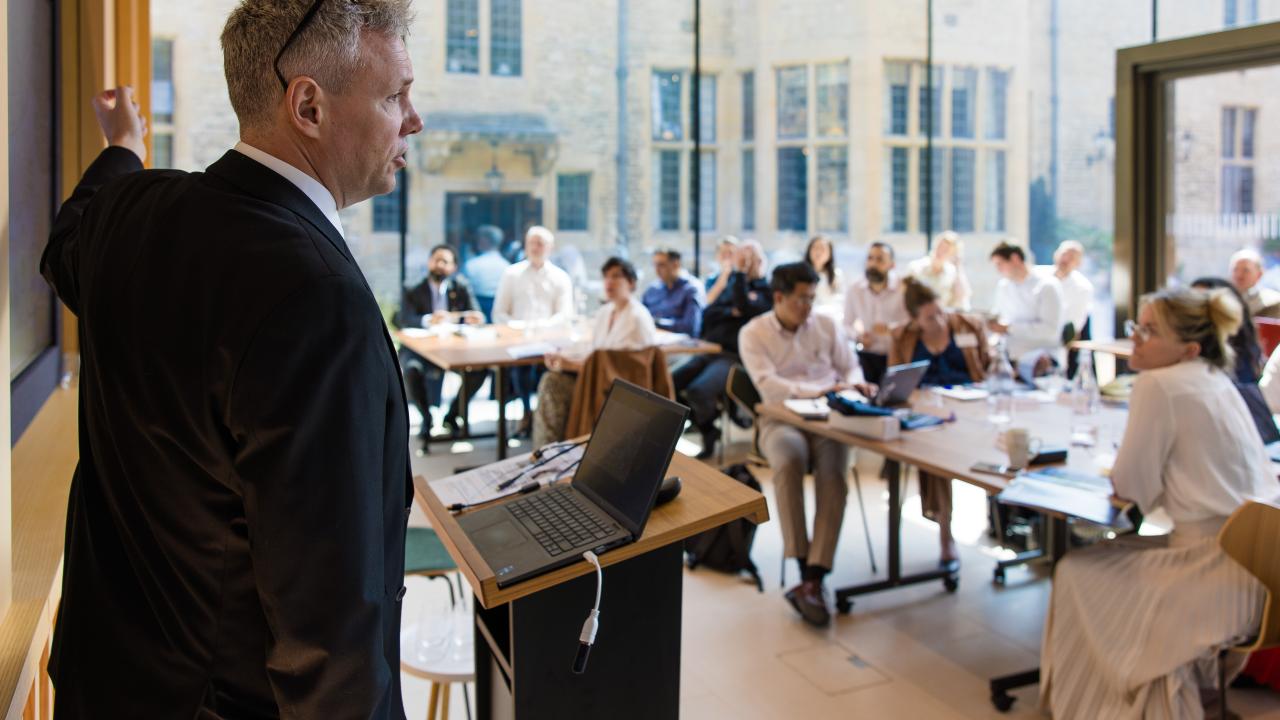 close up image of a man stood in front of an audience giving a lecture