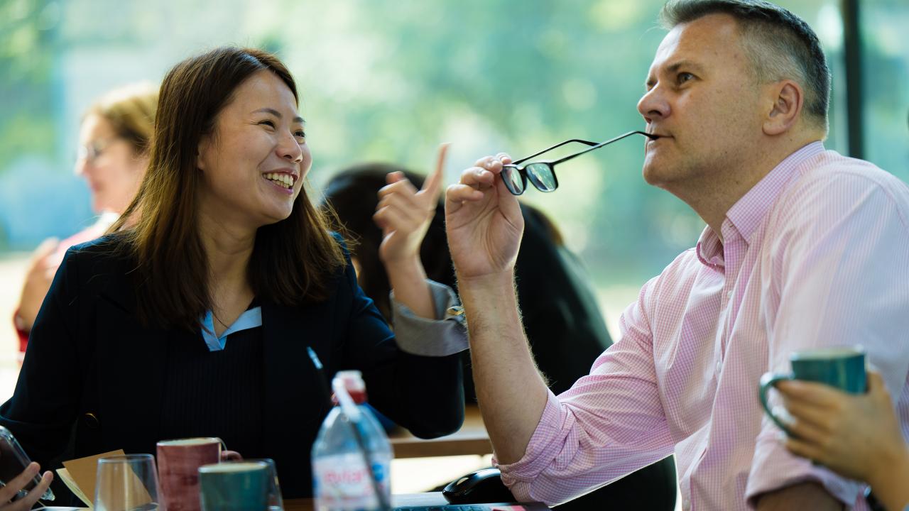 image of a man sat holding a pair of glasses next to a woman smiling