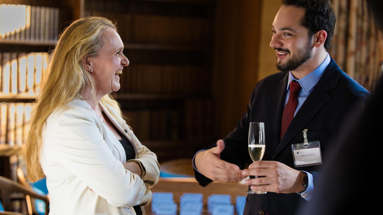 side image of a woman speaking to a man holding a wine glass