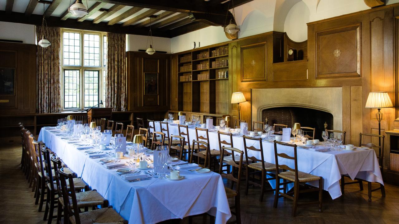 image of two long tables in a room with white tablecloths on them