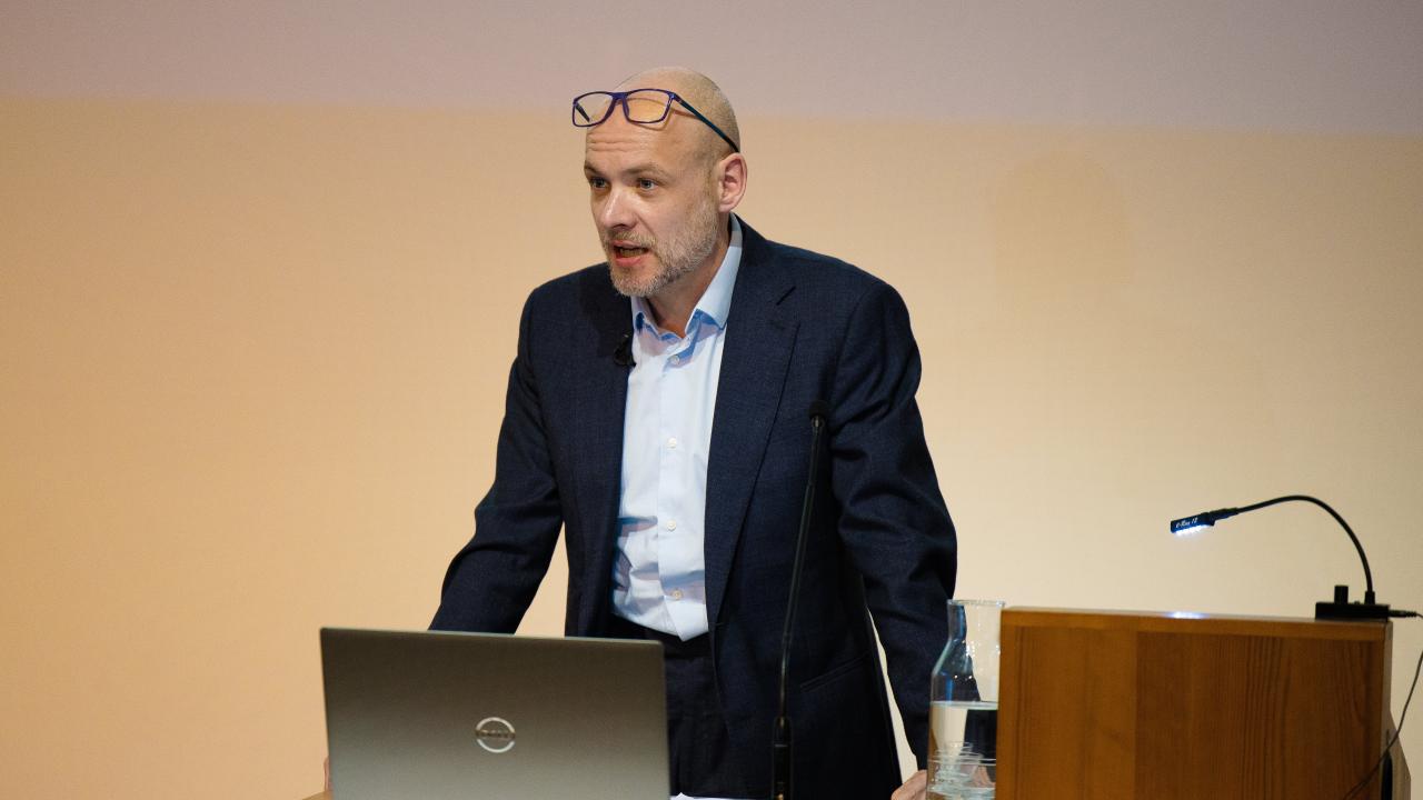 image of a man in front of a laptop speaking