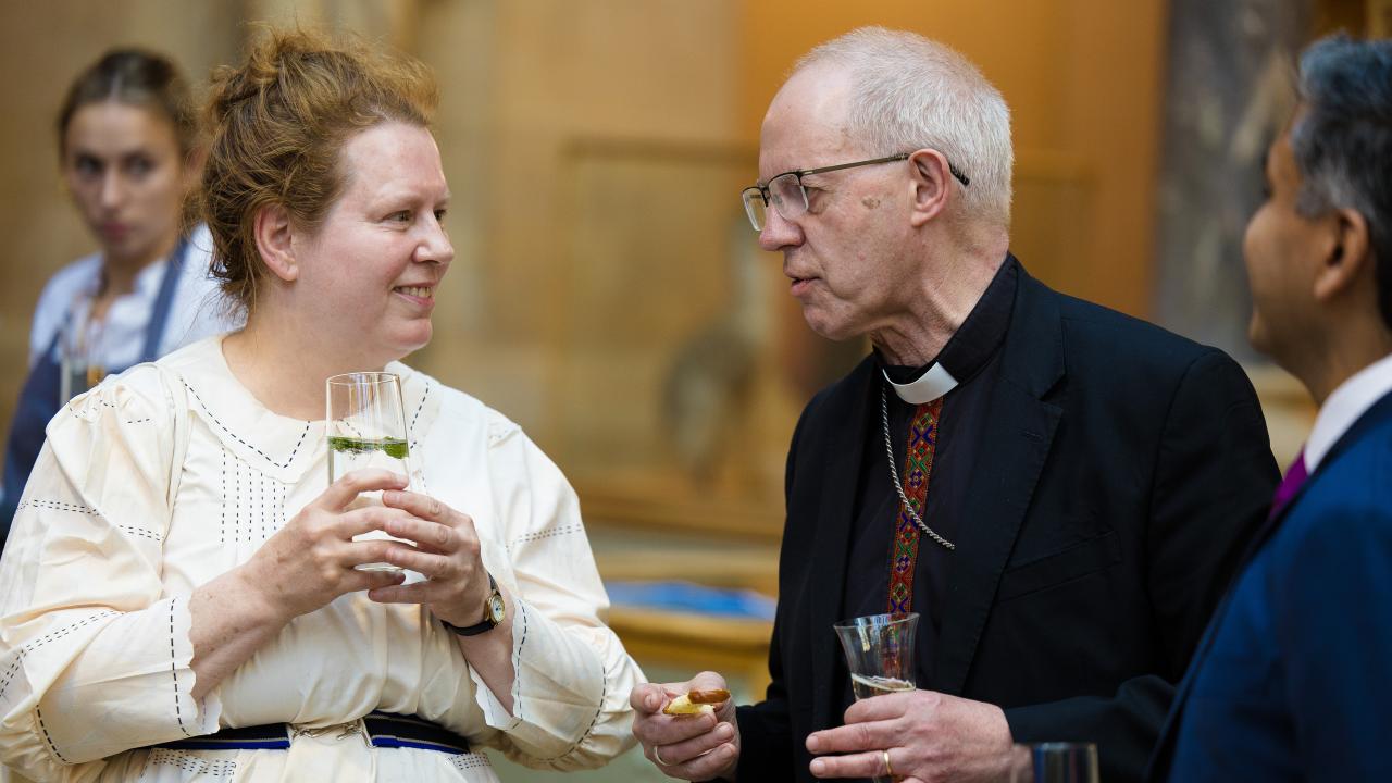 image of woman holding a glass speaking to a man next to her
