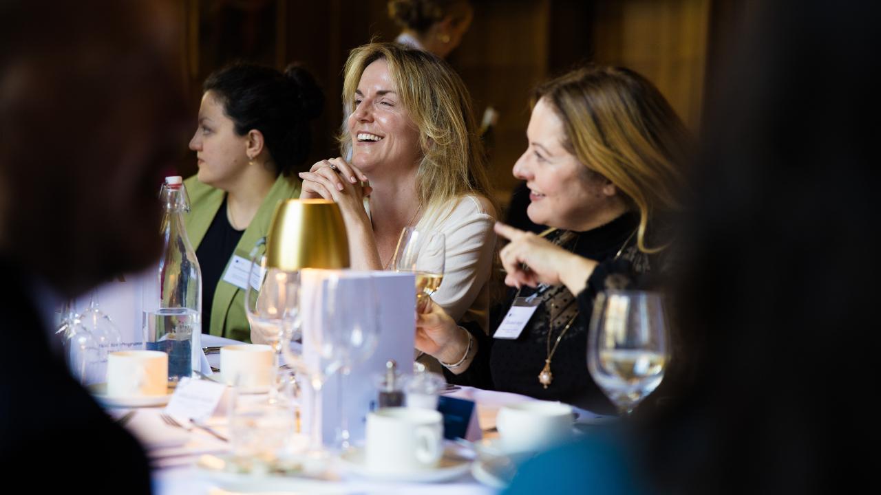image of three women sat at a long table smiling