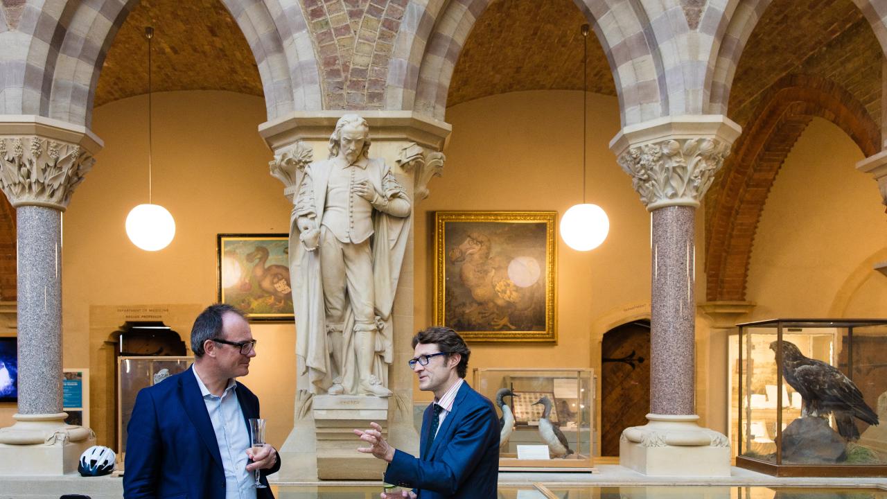 image of two men stood talking in front of a couple of arches