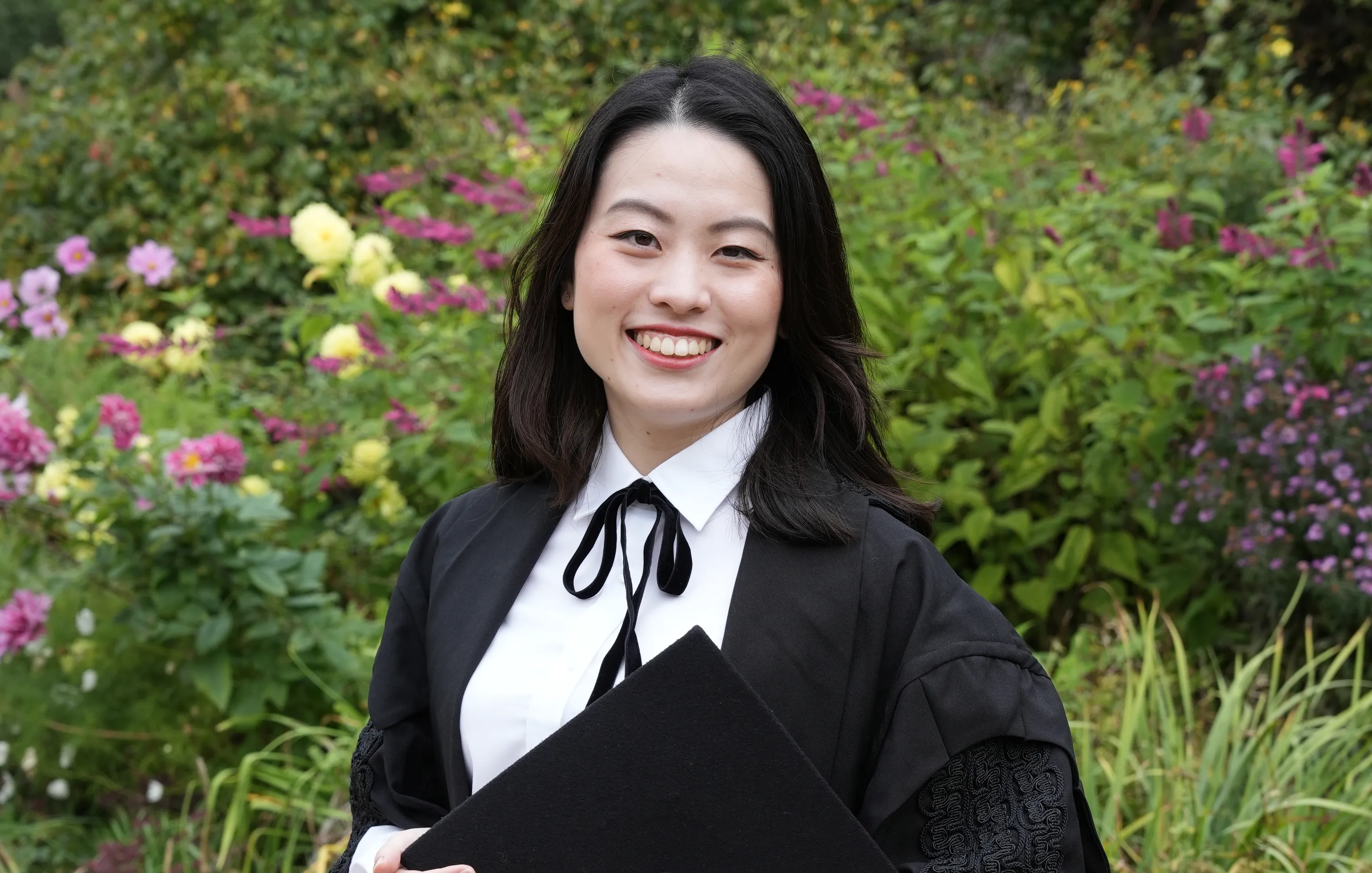 A woman wearing a black gown and white shirt smiling at the camera