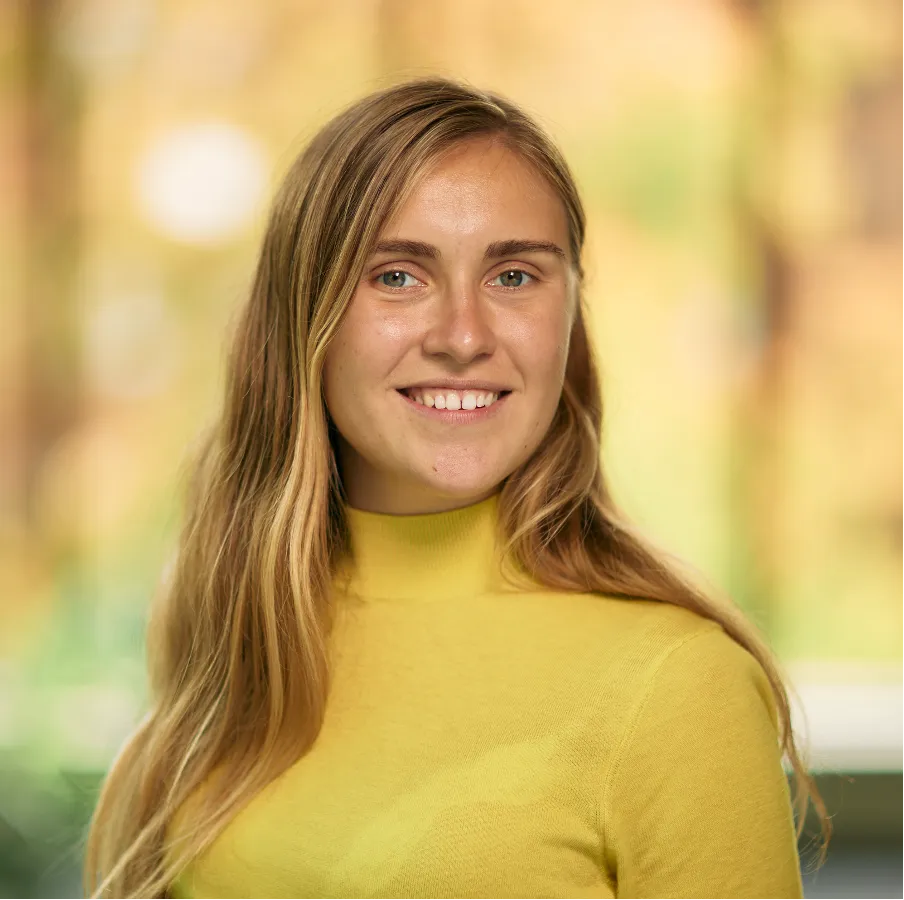 Image of a woman with long hair wearing a yellow top smiling at the camera