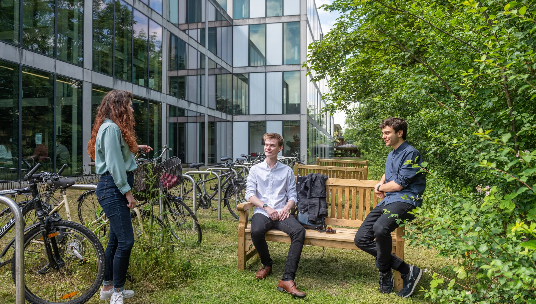 Image of three students outside by a bench