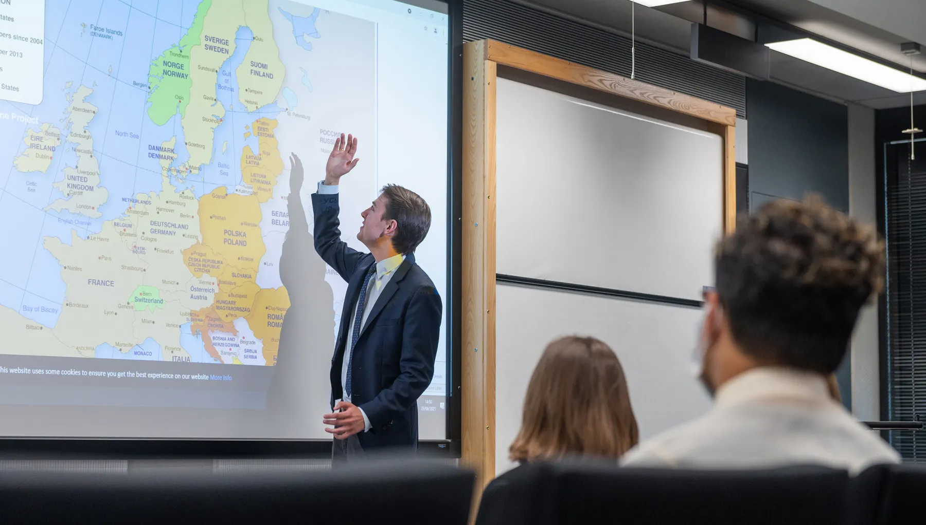 Image of a person pointing at a screen in a classroom