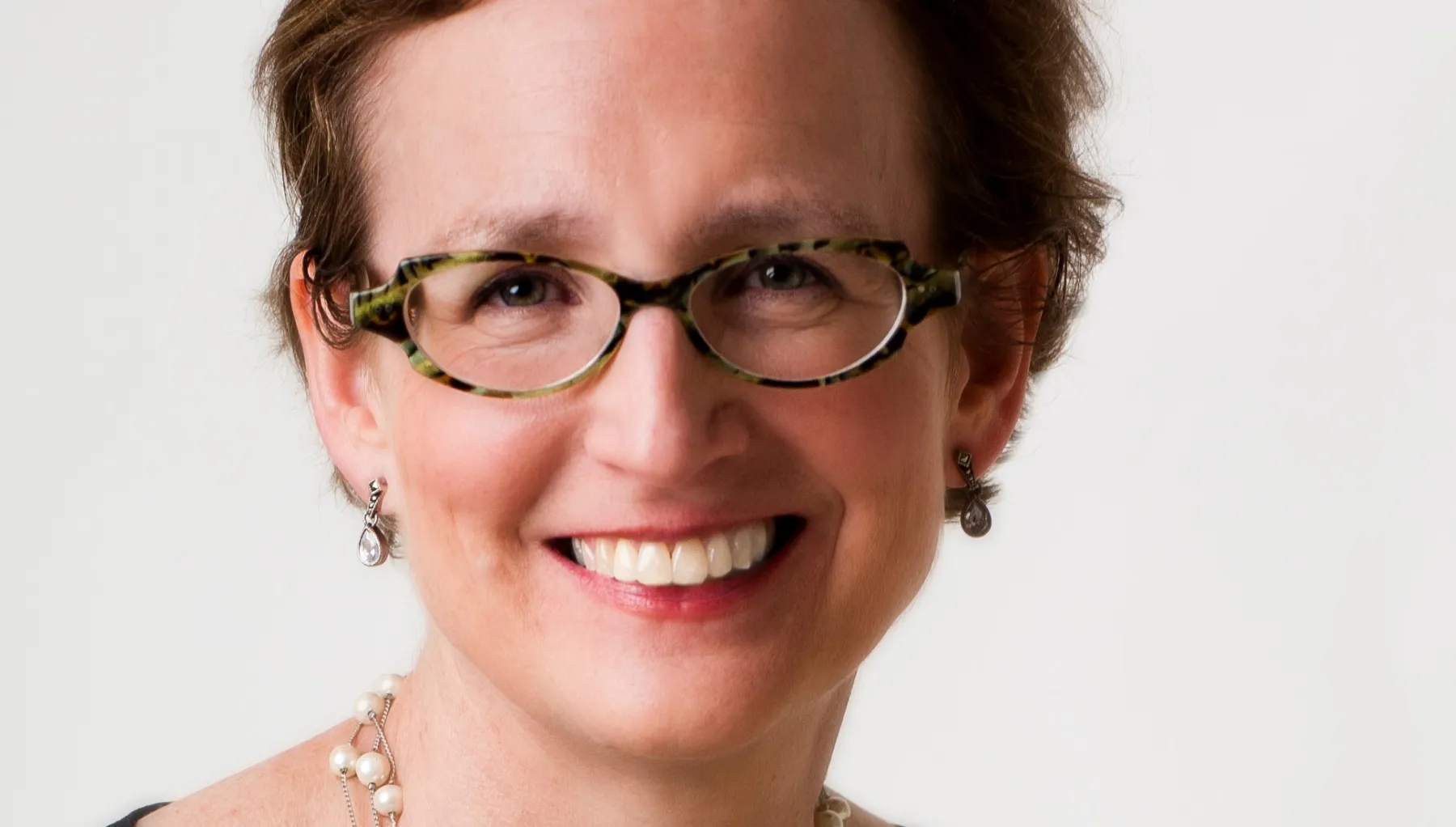 Image of a woman wearing glasses smiling at the camera