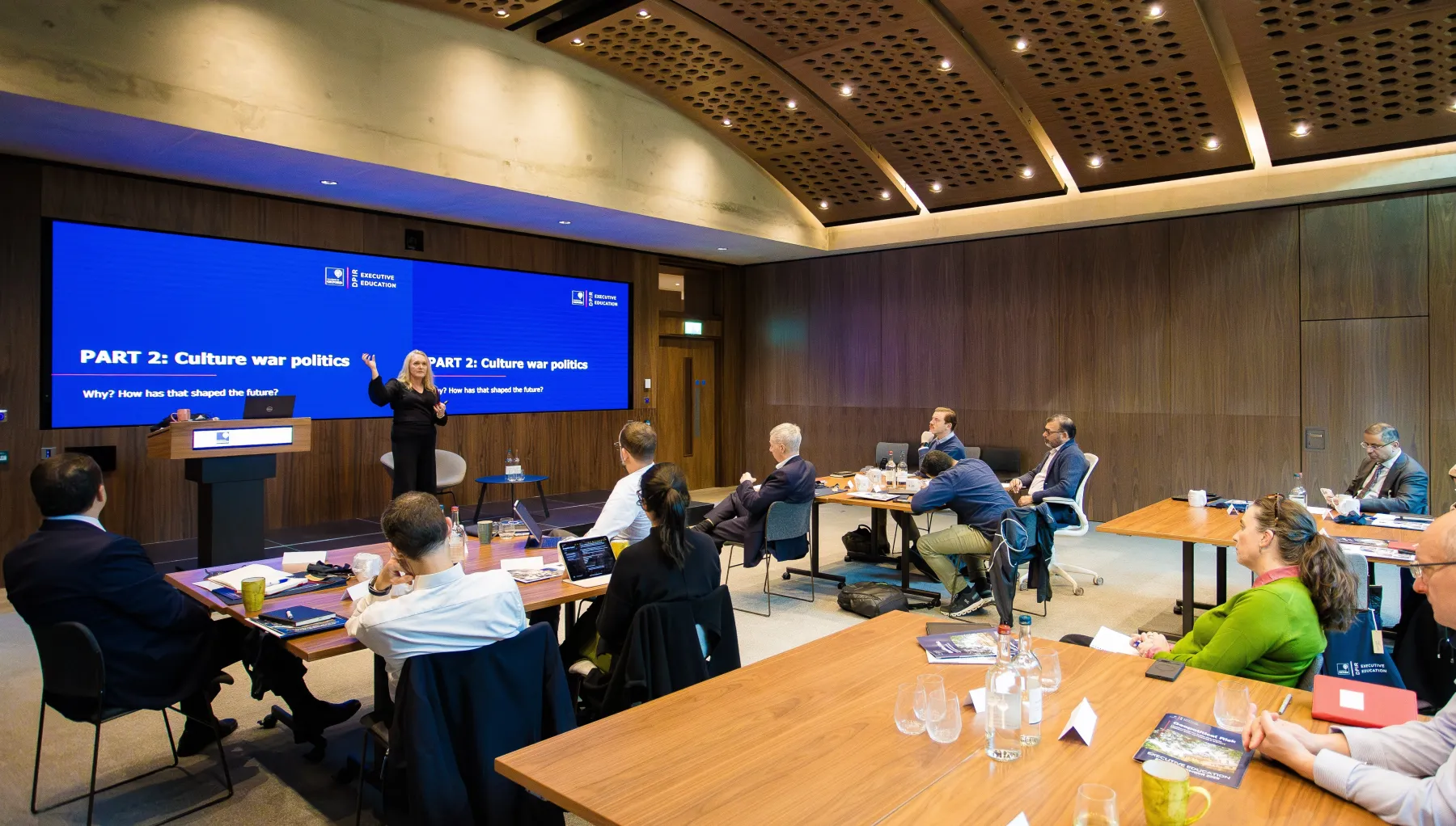 Image of people in a room looking at a presentation on a screen