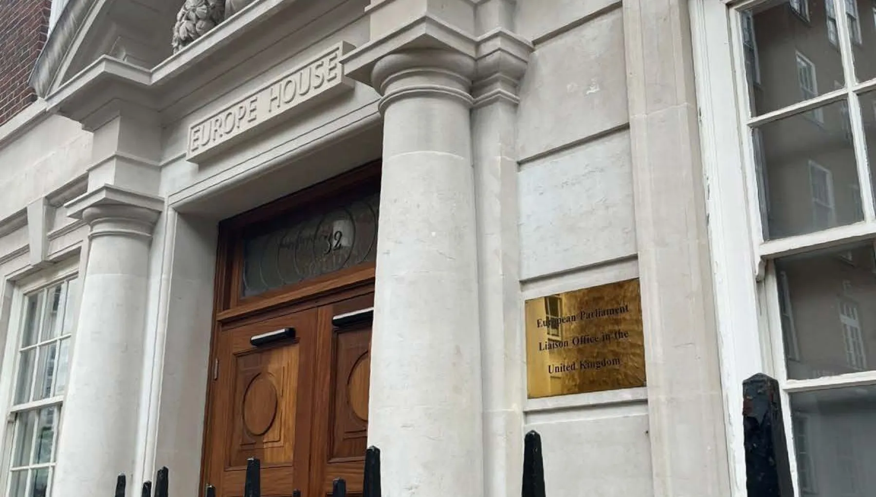 image of a brown door on a property with a white frontage and black railings