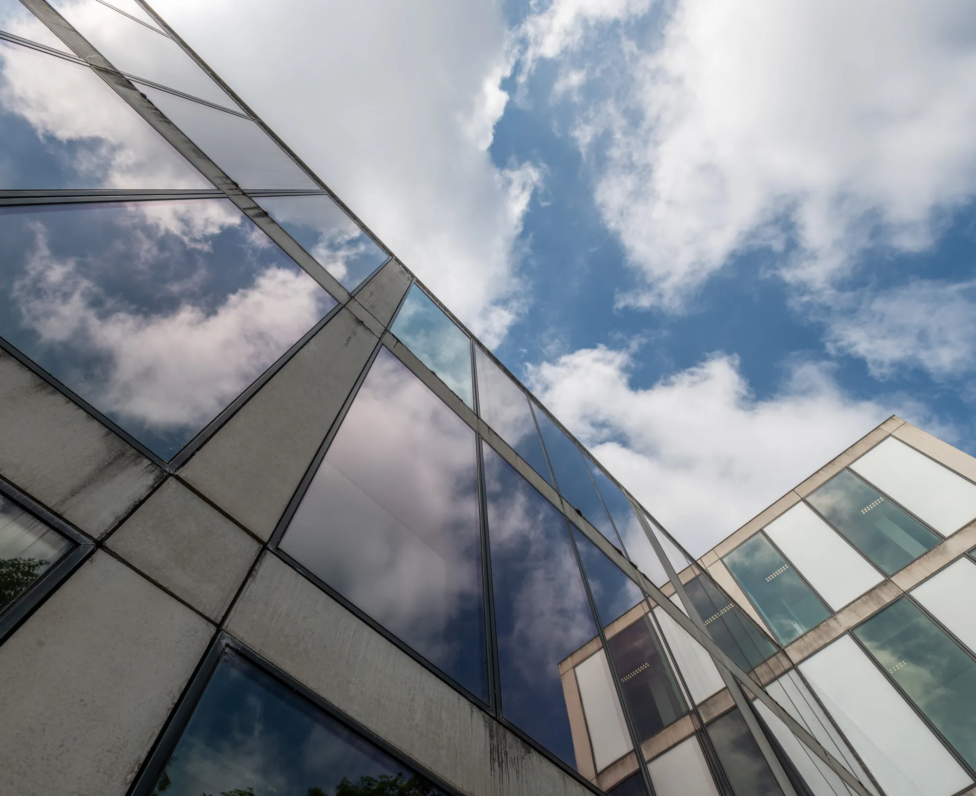 Upwards image of the glasswork of a building set against a cloudy sky. Image