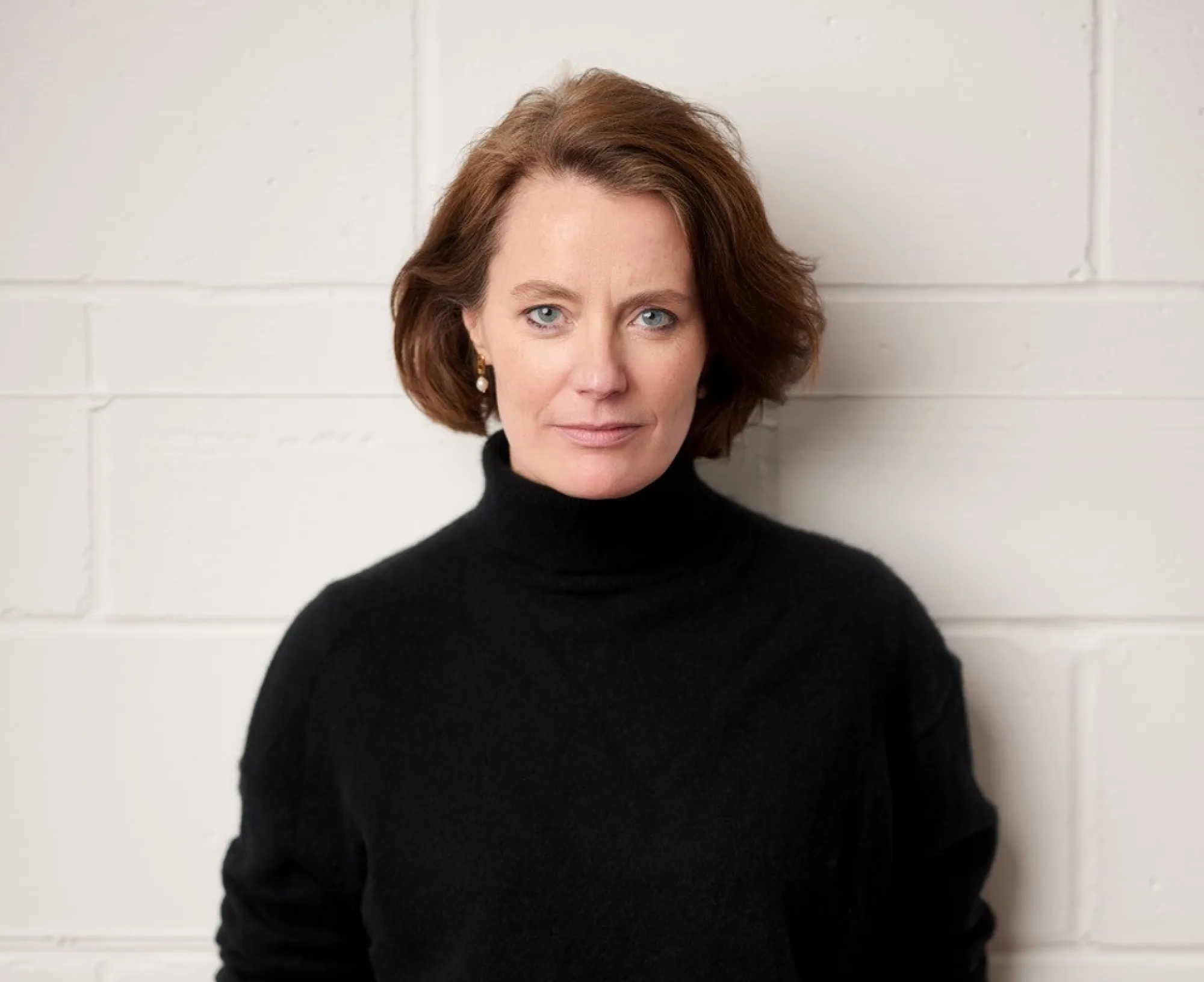 a woman wearing a dark top and blue jeans smiling at camera.