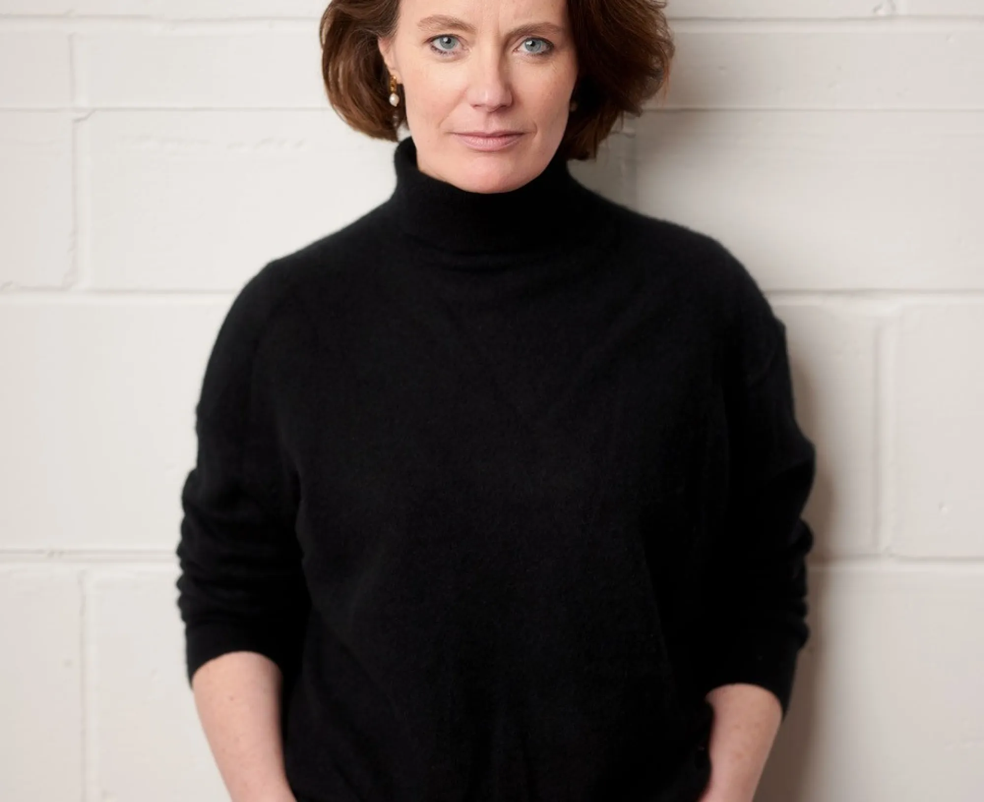 a woman wearing a dark top and blue jeans smiling at camera.
