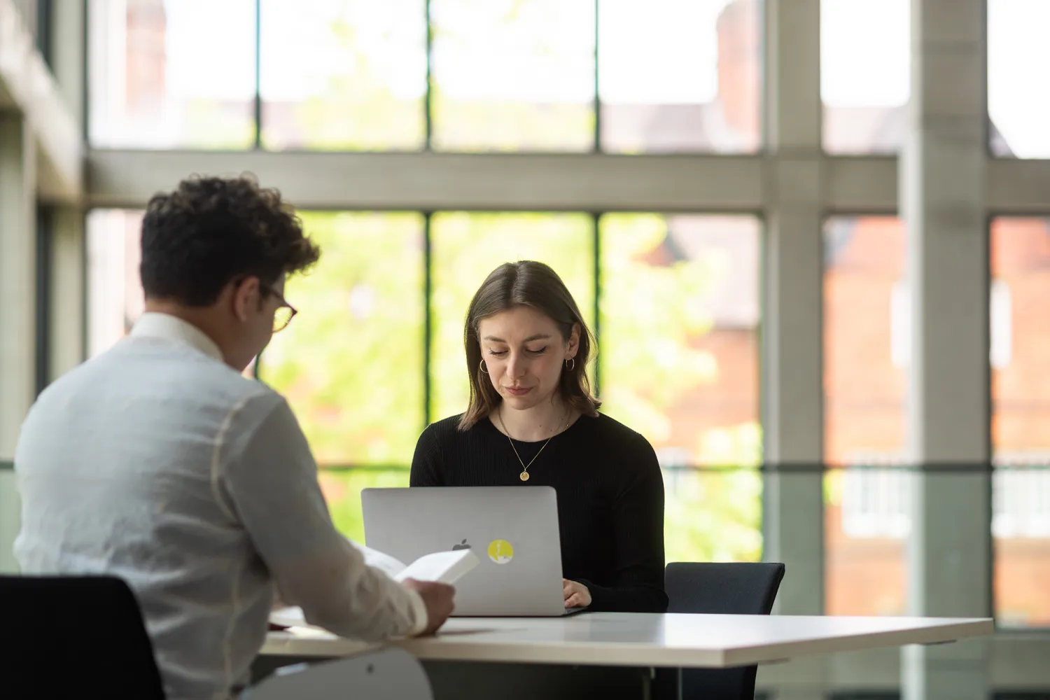 Woman on laptop, man reading book
